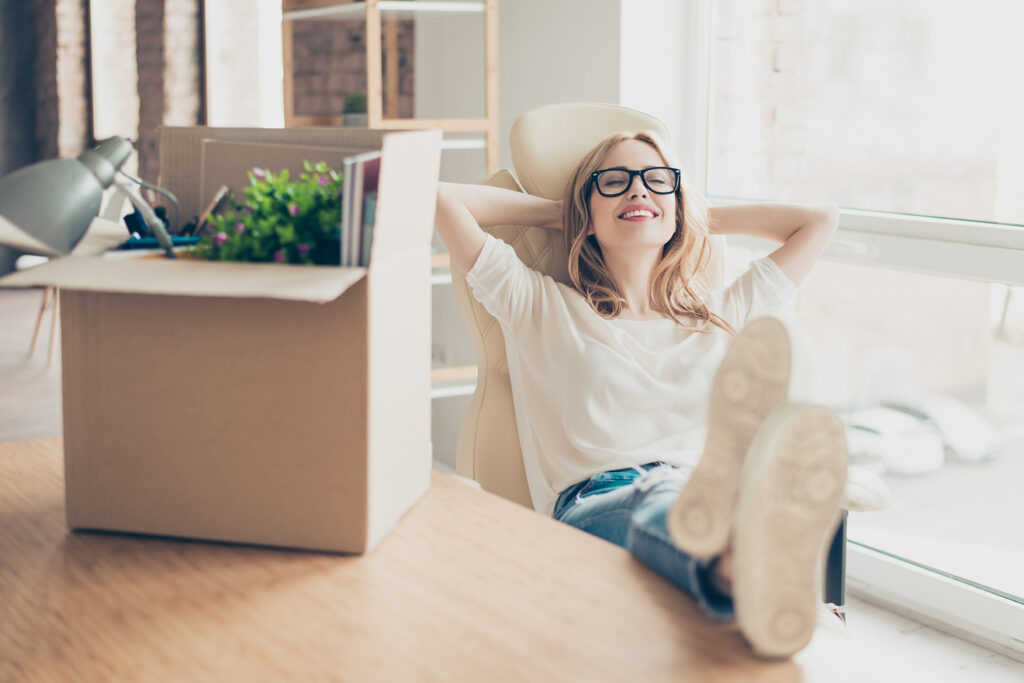 Young woman packing items to go in self-storage enjoying peace of mind sitting at a desk